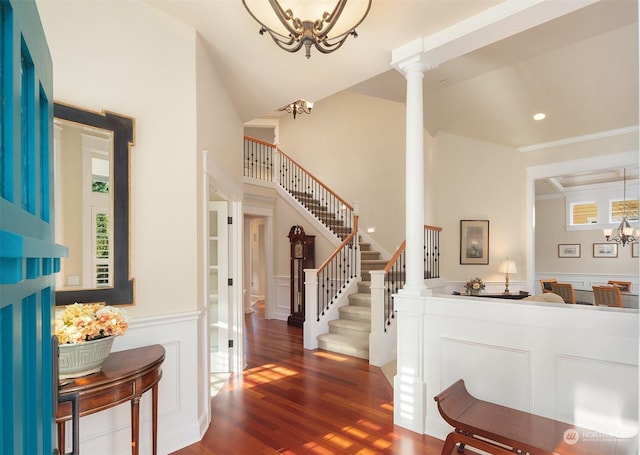 entrance foyer with ornate columns, plenty of natural light, dark wood-type flooring, and an inviting chandelier