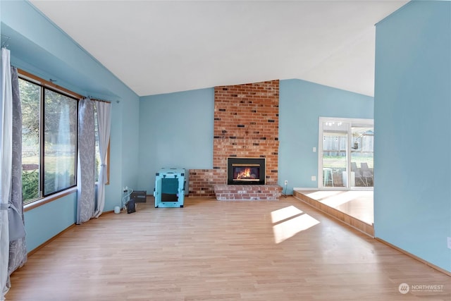 unfurnished living room featuring lofted ceiling, plenty of natural light, and a fireplace