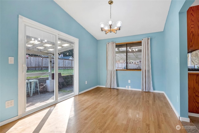 unfurnished dining area with vaulted ceiling, a chandelier, and light hardwood / wood-style flooring