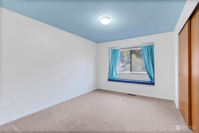 unfurnished bedroom featuring a closet, a textured ceiling, and carpet flooring