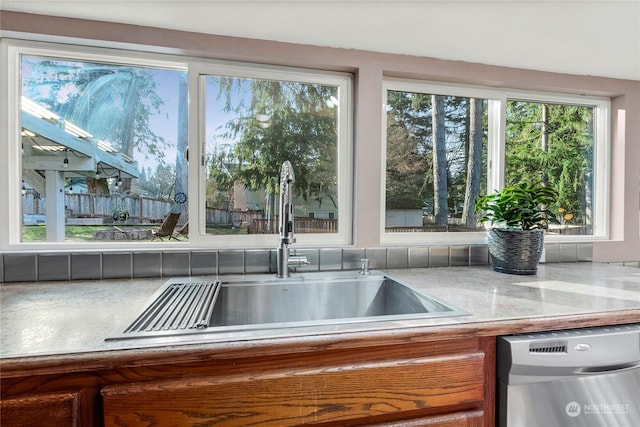 interior space with dishwasher, light stone countertops, and sink