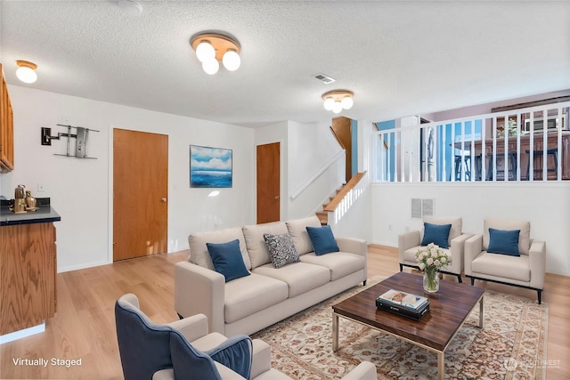 living room featuring a textured ceiling and light wood-type flooring