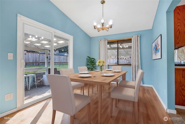 dining space with an inviting chandelier, vaulted ceiling, and hardwood / wood-style floors