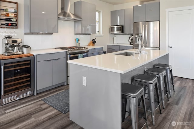 kitchen with sink, wine cooler, a kitchen bar, stainless steel appliances, and wall chimney range hood