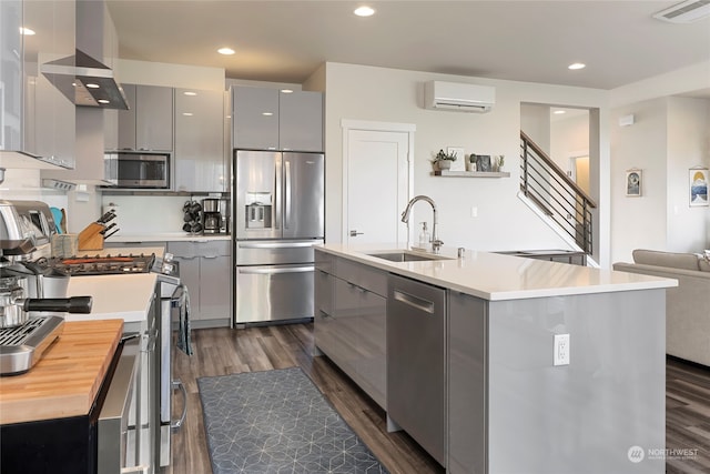 kitchen featuring a center island with sink, a wall unit AC, gray cabinets, and appliances with stainless steel finishes