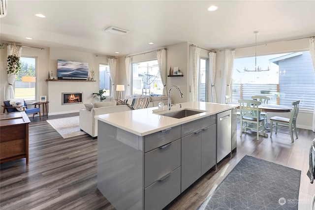 kitchen featuring sink, gray cabinets, an island with sink, dishwasher, and pendant lighting