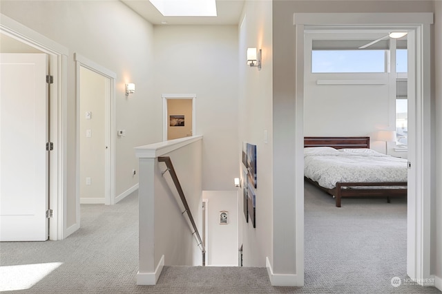 hall featuring light colored carpet and a skylight