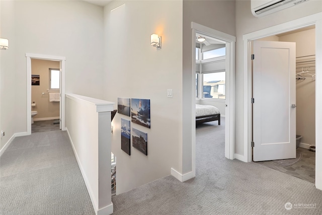 corridor with light carpet and a wall unit AC