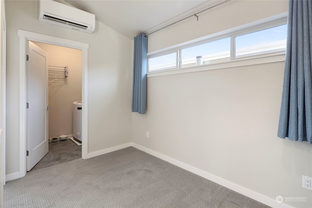 unfurnished bedroom featuring a wall mounted air conditioner, a spacious closet, light carpet, a closet, and washer / clothes dryer