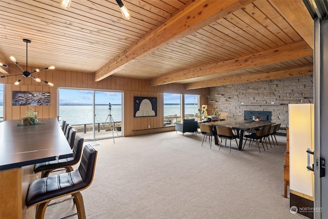 dining area featuring a water view, wooden ceiling, a notable chandelier, beam ceiling, and carpet