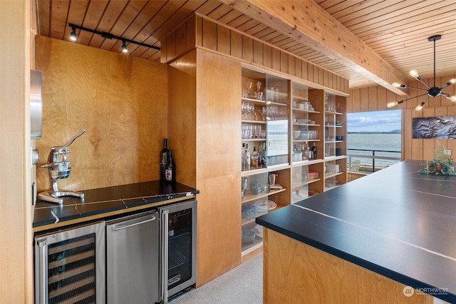 kitchen with beam ceiling, wooden walls, beverage cooler, and a water view