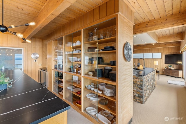 interior space with sink, wood walls, light carpet, wooden ceiling, and beam ceiling