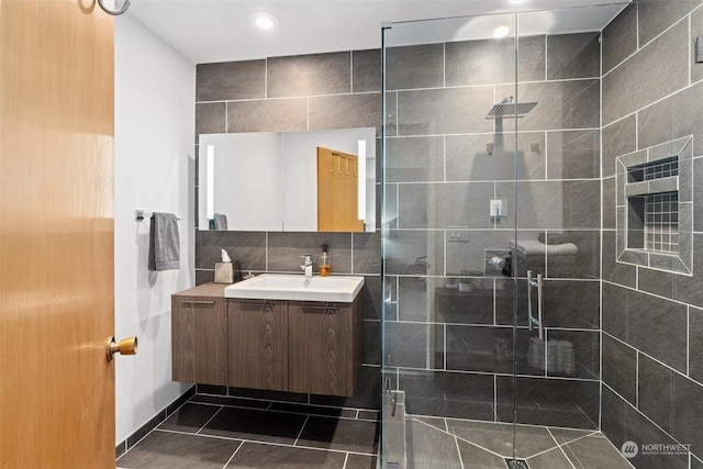 bathroom with tile patterned flooring, vanity, backsplash, and walk in shower