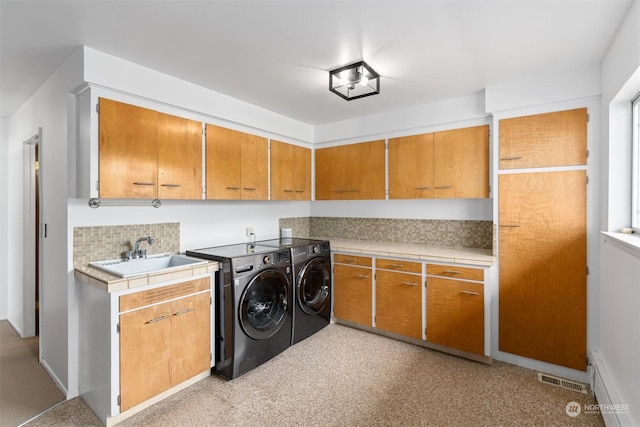 washroom with cabinets, washing machine and dryer, and sink