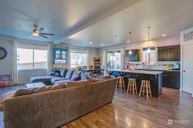 living room with dark hardwood / wood-style flooring, sink, ceiling fan, and beam ceiling