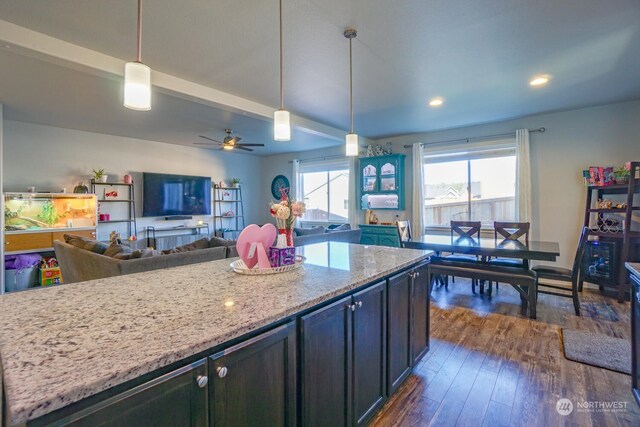 kitchen with decorative light fixtures, dark hardwood / wood-style flooring, ceiling fan, light stone counters, and beam ceiling