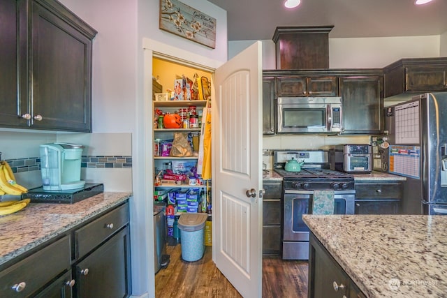 kitchen featuring tasteful backsplash, stainless steel appliances, dark hardwood / wood-style flooring, and light stone countertops