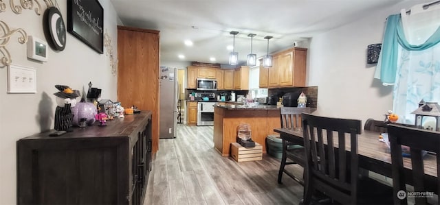 kitchen with light hardwood / wood-style flooring, backsplash, hanging light fixtures, stainless steel appliances, and kitchen peninsula