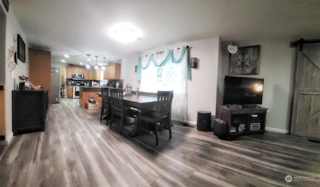 dining area with wood-type flooring and a barn door