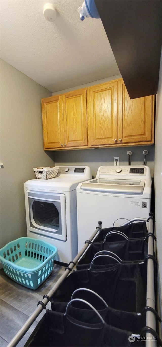 clothes washing area featuring cabinets and washing machine and clothes dryer