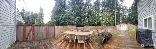 wooden deck with a storage shed and grilling area