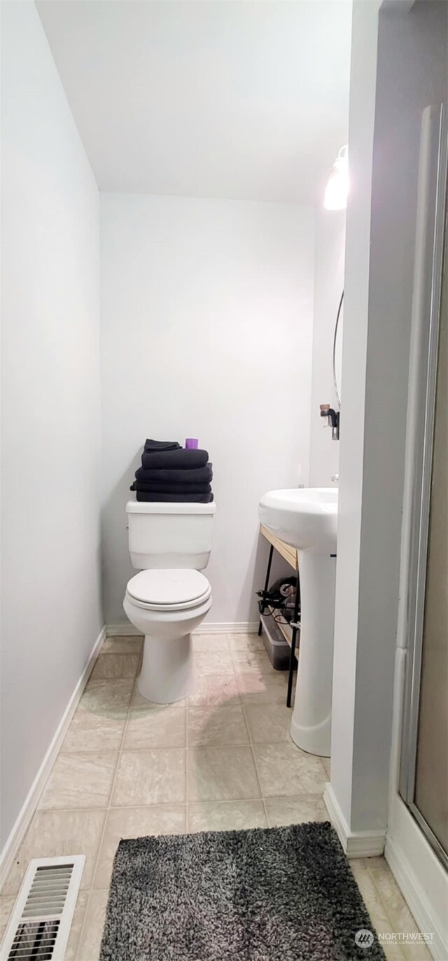 bathroom with a shower with shower door, tile patterned floors, and toilet