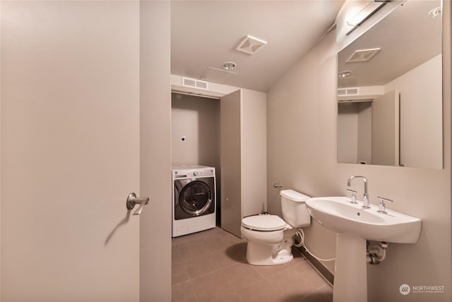 bathroom featuring washer / clothes dryer, tile patterned floors, and toilet