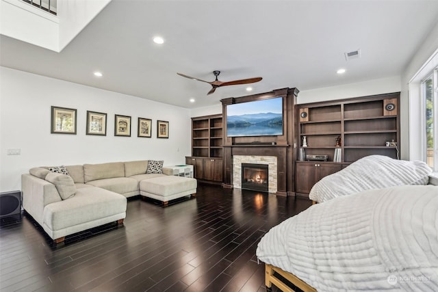 living room with ceiling fan, a stone fireplace, and dark hardwood / wood-style flooring