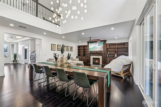 dining space featuring a stone fireplace, plenty of natural light, dark hardwood / wood-style floors, and ceiling fan