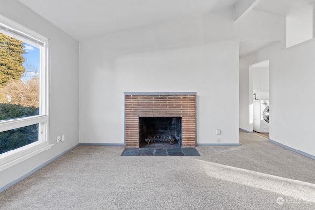 unfurnished living room with a brick fireplace, carpet floors, washing machine and dryer, and lofted ceiling with beams