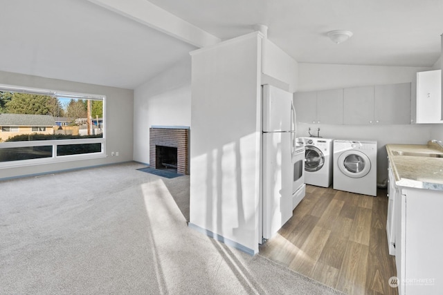 washroom with washer and dryer, a brick fireplace, sink, and light hardwood / wood-style flooring