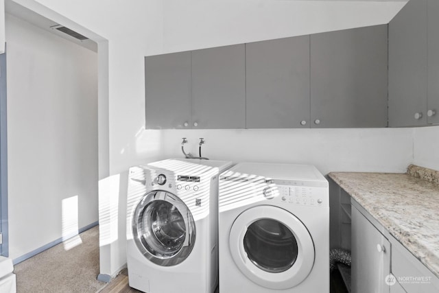 washroom featuring cabinets, washer and dryer, and light colored carpet