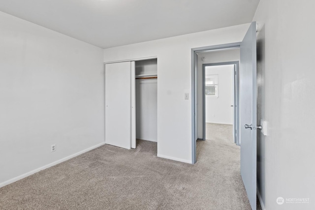 unfurnished bedroom with light colored carpet and a closet