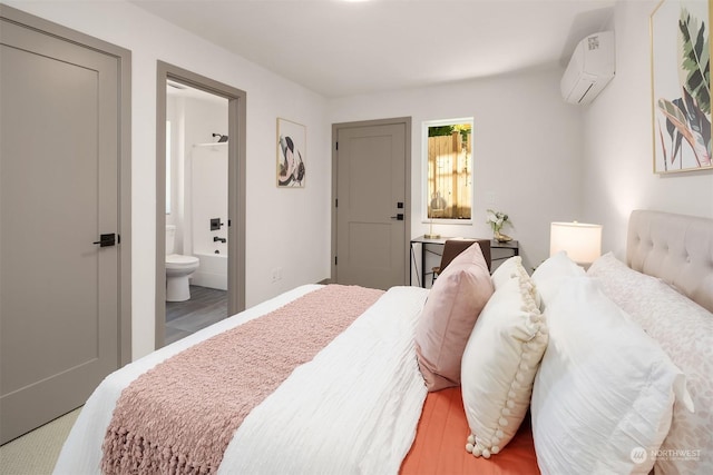 bedroom with hardwood / wood-style floors, a wall unit AC, and ensuite bath