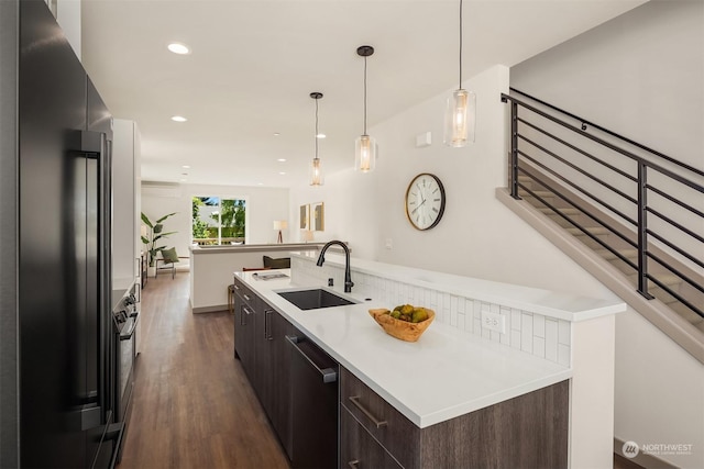 kitchen with sink, high end refrigerator, dark brown cabinets, dark hardwood / wood-style flooring, and stainless steel dishwasher