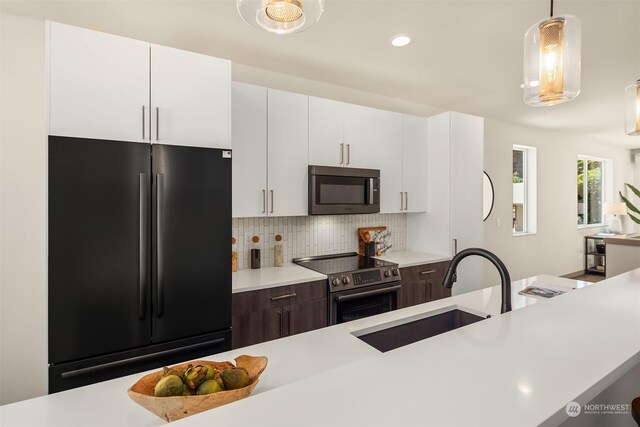 kitchen featuring appliances with stainless steel finishes, pendant lighting, sink, white cabinets, and dark brown cabinetry