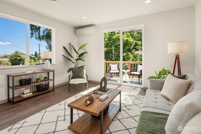 living room with hardwood / wood-style flooring, a wall unit AC, and a wealth of natural light