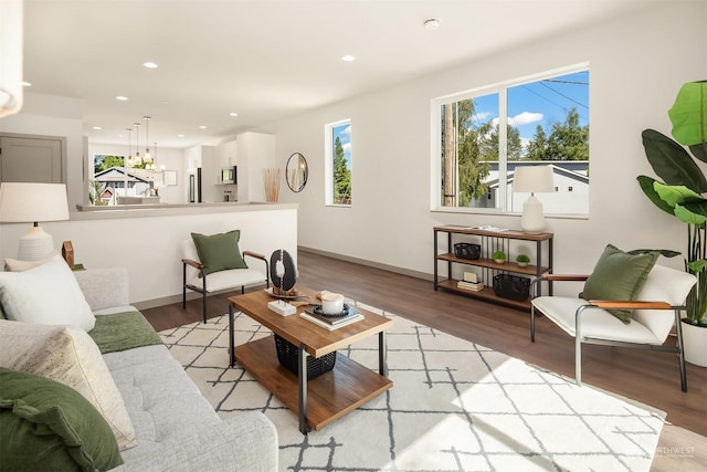 living room with an inviting chandelier, a wealth of natural light, and light wood-type flooring