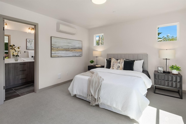 bedroom with ensuite bathroom, a wall mounted AC, and light colored carpet