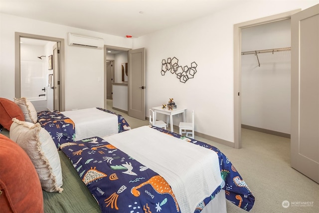 bedroom featuring ensuite bath, a spacious closet, an AC wall unit, a closet, and carpet