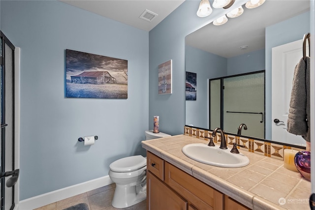 bathroom featuring tile patterned flooring, vanity, a shower with shower door, and toilet