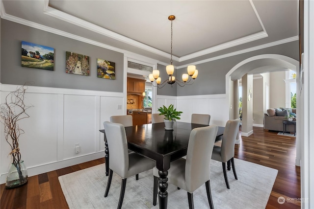 dining space featuring crown molding, a healthy amount of sunlight, dark hardwood / wood-style flooring, and a raised ceiling