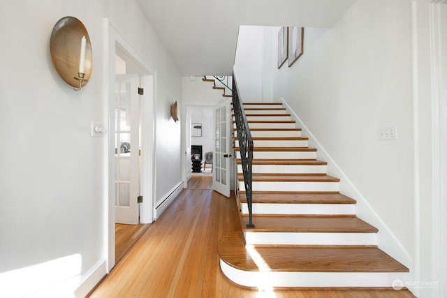 stairs with wood-type flooring and baseboard heating