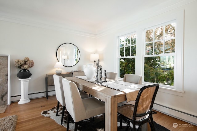 dining room featuring ornamental molding, a healthy amount of sunlight, baseboard heating, and light hardwood / wood-style floors