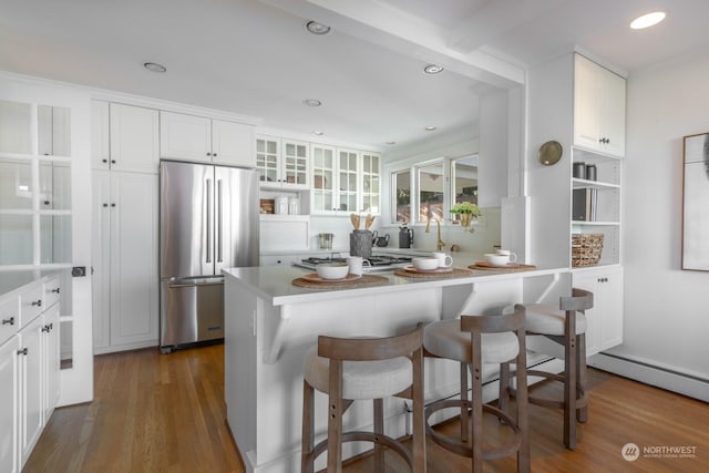 kitchen featuring dark hardwood / wood-style floors, a breakfast bar, white cabinets, and appliances with stainless steel finishes