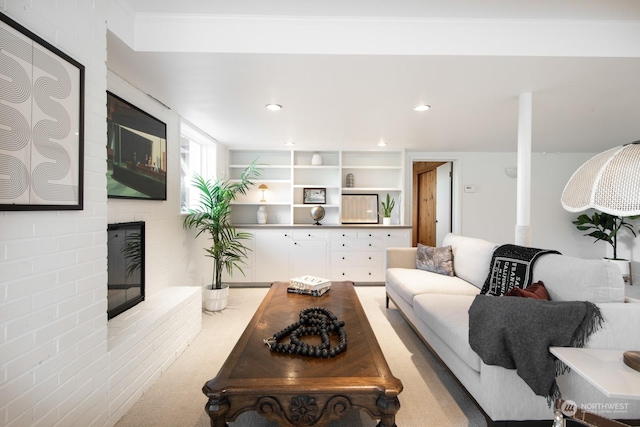 living room with crown molding, a brick fireplace, and light carpet