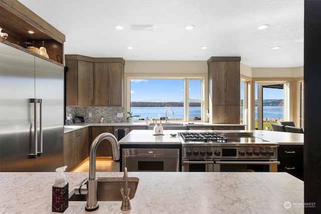 kitchen featuring a water view, dark brown cabinetry, a healthy amount of sunlight, and premium appliances