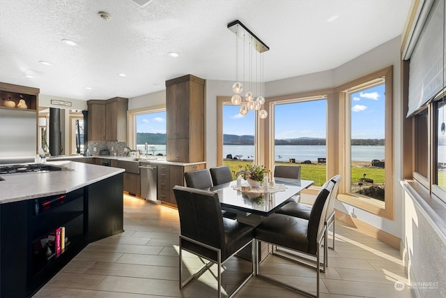 dining space featuring a water view and a textured ceiling