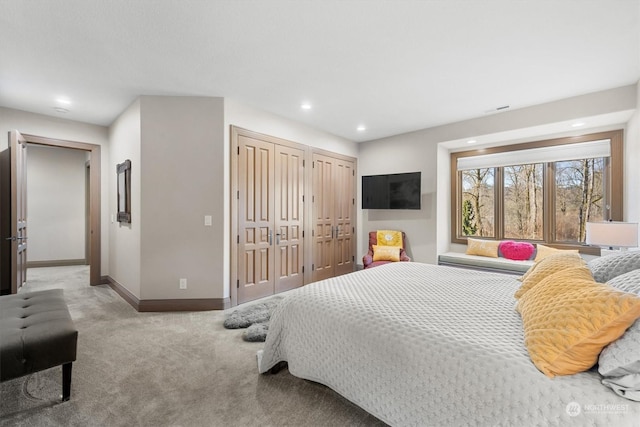 bedroom with light colored carpet and two closets