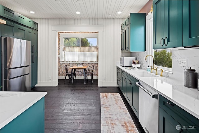 kitchen with a sink, light stone countertops, dark wood-style floors, stainless steel appliances, and green cabinetry